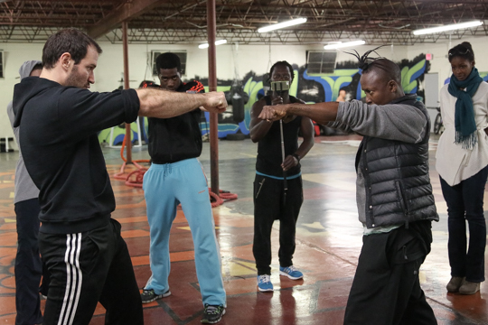 Dr. Joab Corey demonstrates boxing techniques for Chipaumire and collborators