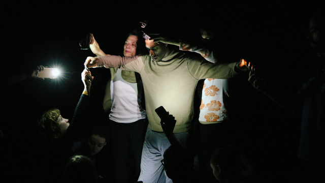 James Raney illuminated by cell phones during rehearsal