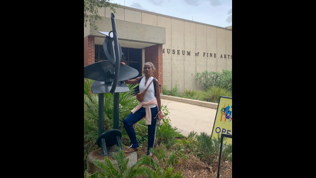 love poses with her father Ed Love's sculpture in FSU's Ed Love Sculpture Garden